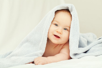 smiling baby is looking from under the towel