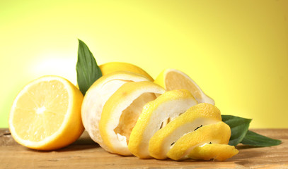 Naklejka na ściany i meble ripe lemons with leaves on wooden table on green background