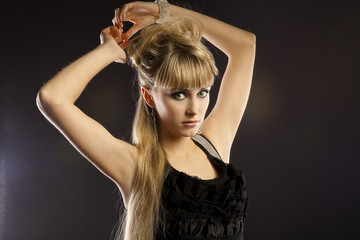 blonde young woman in black dress posing in studio