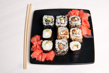 Sushi on a black plate on white table.