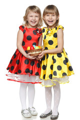 Full length of two little girls holding basket with Easter eggs