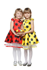 Full length of two little girls holding basket with easter eggs