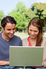 Two friends smiling as they watch something on a tablet