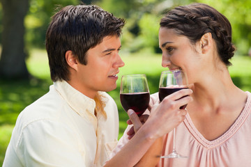 Two friends linking their arms while holding glasses of wine