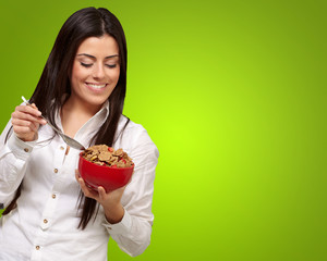 portrait of healthy young woman eating cereals over green