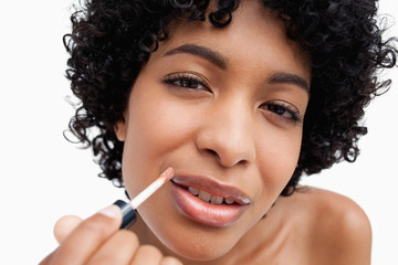 Obraz premium Beautiful teenage girl applying lipstick against a white backgro