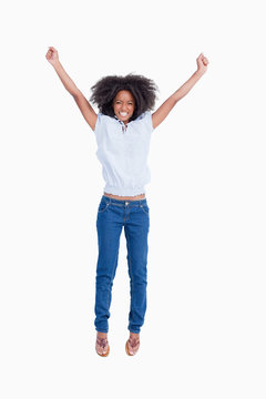 Young woman beaming while raising her arms above the head