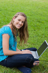 Young smiling girl looking at the camera while using her laptop