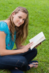 Obraz premium Young relaxed girl reading a book while sitting in the countrysi