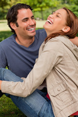 Obraz premium Two friends gleefully laughing as they are sitting next to each
