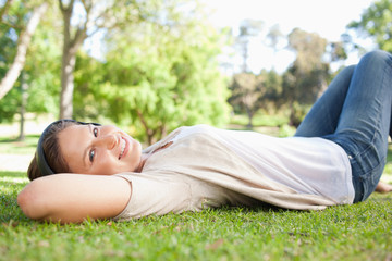 Woman lying on the grass while listening to music
