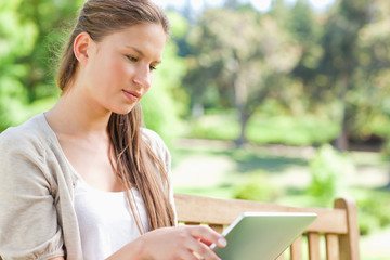 Obraz premium Woman with her tablet computer sitting on a park bench