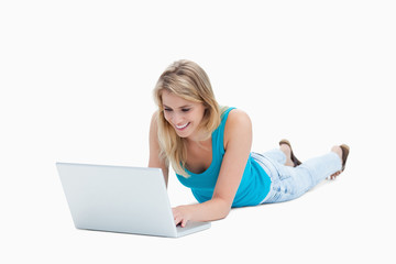 A young woman lying on the floor with a laptop