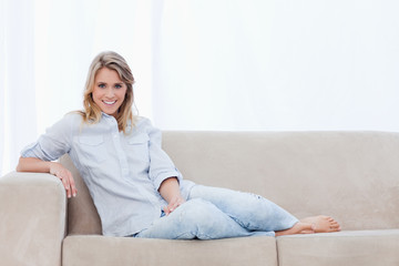 A woman smiling at the camera is sitting on a couch