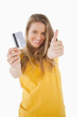 Fototapeta premium Portrait of a blonde student tending a credit card with the thum