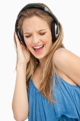 Fototapeta premium Close-up of a beautiful young woman singing while listening to m