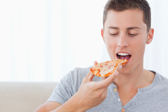 A Man Looking At The Slice Of Pizza He Is About To Eat