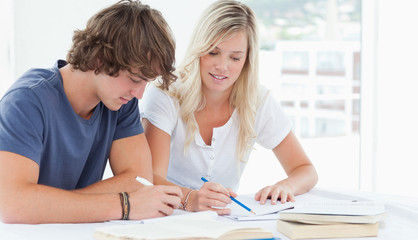 Obraz premium A man and woman working together at doing homework