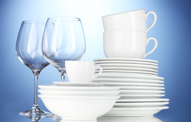 empty bowls, plates, cups and glasses on blue background