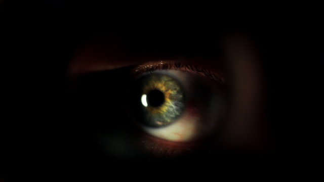 Mans eye looking through a blured hole