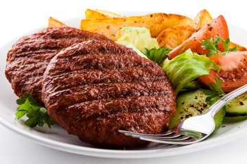 Grilled beefsteaks, baked potatoes and vegetable salad