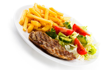 Grilled steaks, French fries and vegetables