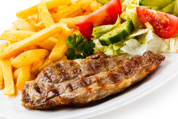 Grilled steaks, French fries and vegetables