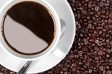Coffee cup and saucer on coffee beans
