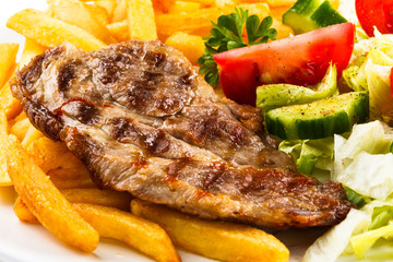 Grilled steaks, French fries and vegetables