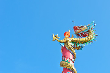 chinese dragon wrap on pole with red ball in blue sky