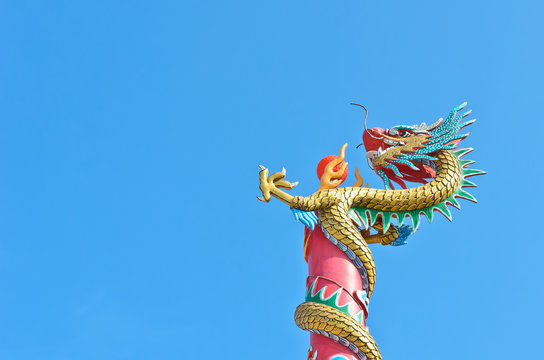 chinese dragon wrap on pole with red ball in blue sky