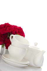 White crockery for tea and a bouquet of roses