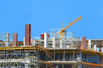 Building crane and building under construction against blue sky