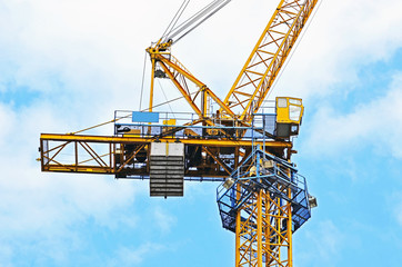 Yellow construction tower crane against blue sky