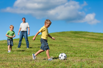 Glückliche Familie spielt Fußball im Sommer