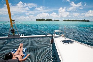 Young woman sunbathing on the catamaran - obrazy, fototapety, plakaty