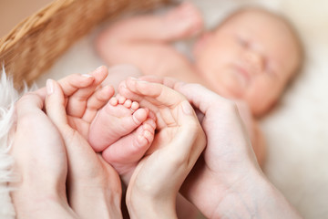 Obraz na płótnie Canvas parenting hands holding small baby's feet
