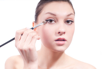 Woman applying eye shadow isolated on white