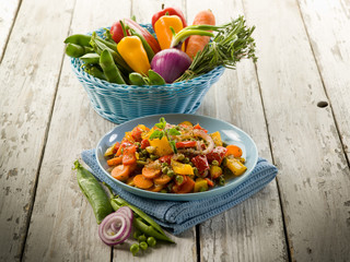 mixed sauteed vegetables on dish over wood background