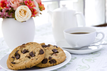 Chocolate chip cookie  on white plate with black coffee and flow