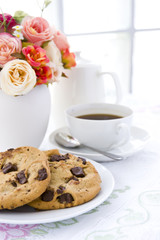 Chocolate chip cookie  on white plate with black coffee and flow