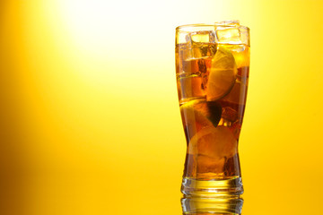 Iced tea with lemon and lime on yelow background