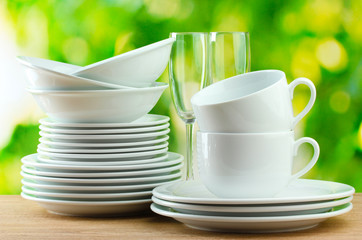 Clean dishes on wooden table on green background