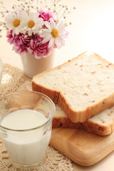 Milk and wheat bread with flower on background