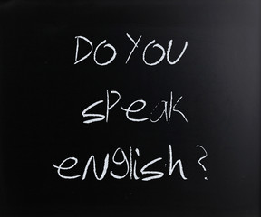 "Do you speak english" handwritten with white chalk on a blackbo