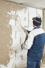Plasterer at stucco work with liquid plaster