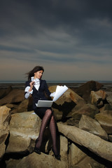 Business lady sitting on the rocks by the sea