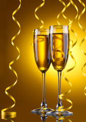 glasses of champagne and streamer on yellow background