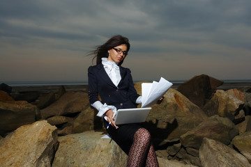 Business lady sitting on the rocks by the sea