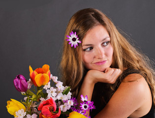 Obraz na płótnie Canvas Jest wiosna: poważnie wyglądający, młoda kobieta z kwiatami